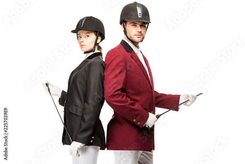 Fotografi serious young equestrians in uniform and helmets holding horseman sticks while l