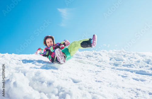 Happy little girl slides down from the snow slope