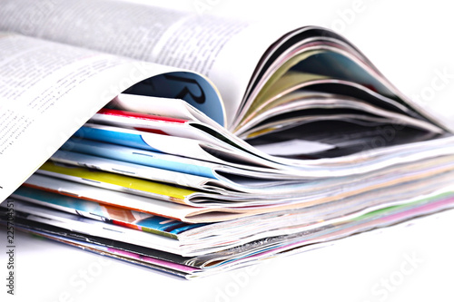 Close up pile of magazines on white background, shallow focus