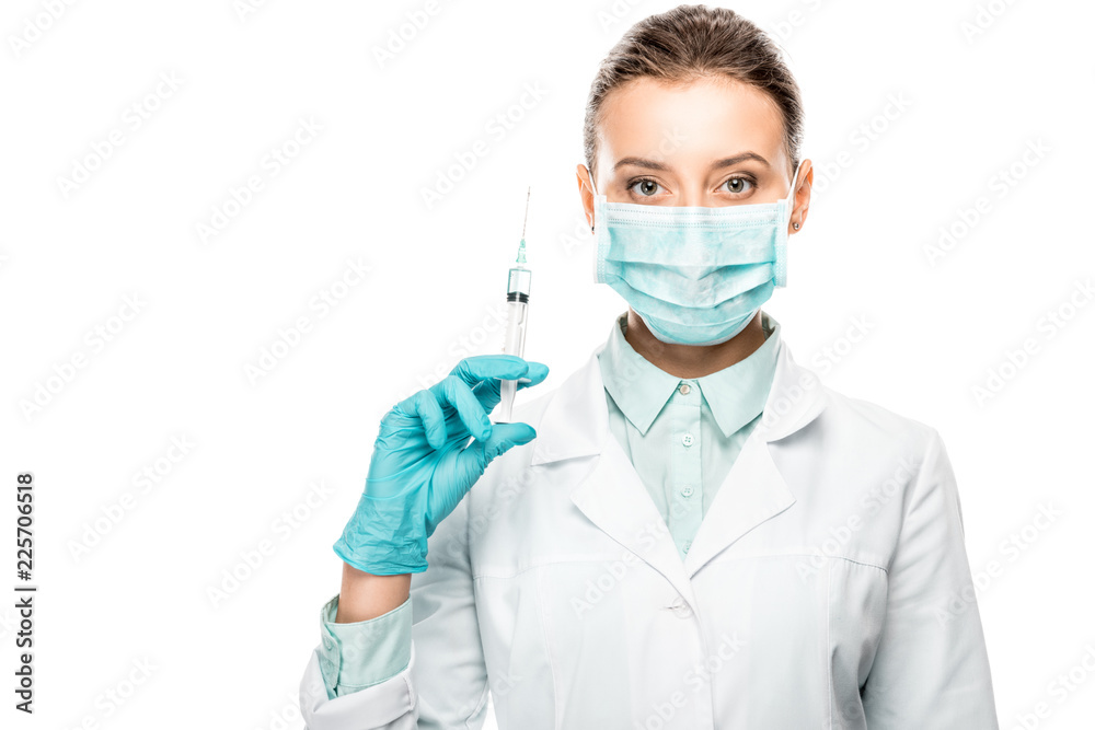 serious female doctor in medical mask holding syringe isolated on white