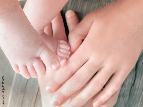 Family background. Daddy s hand holding newborn baby s feet. Child s fingers on father s hand. Closup. Veiw from above.