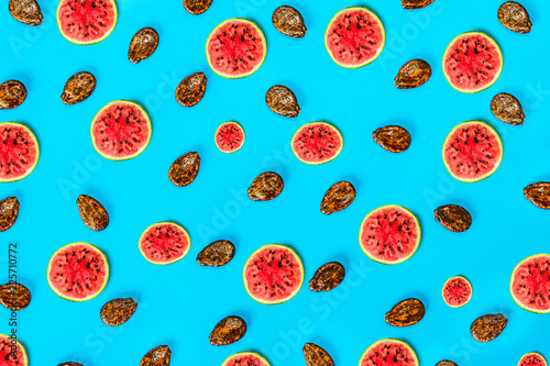 Pattern food background from the pulp of watermelon on a round slice and seeds, view from above closeup, the texture of the food against the background of colored paper, 