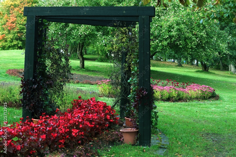 A garden with a wooden arch and flowers next to the clay pots. A garden with a wooden arch and flowers next to the clay pots.