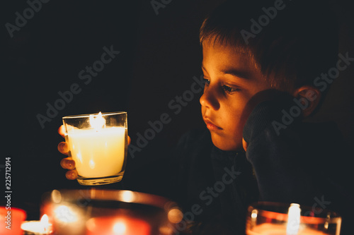 Child in the dark looks at candles