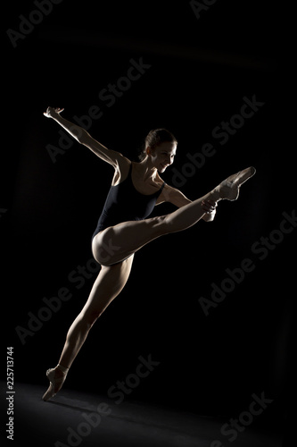 In the photo studio a young ballerina with a beautiful body dances. © Andrey