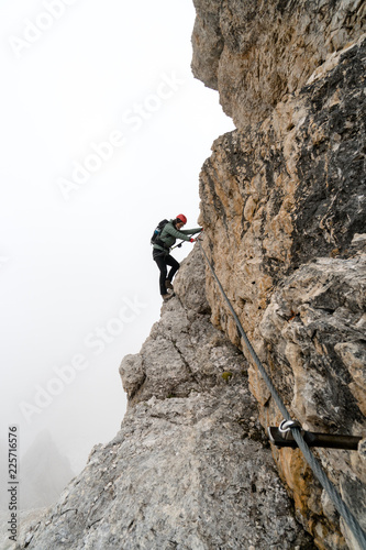 young female climber on a steep and exposed rock face climbing a Via Ferrata