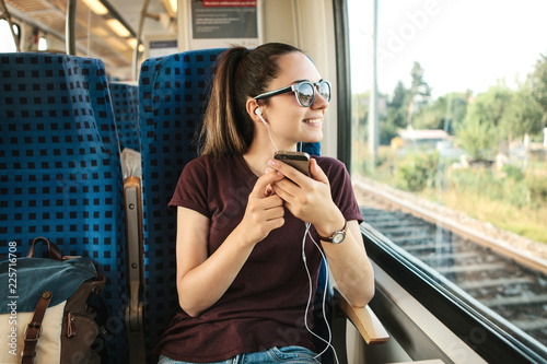 A young girl listens to a music or podcast while traveling in a train.