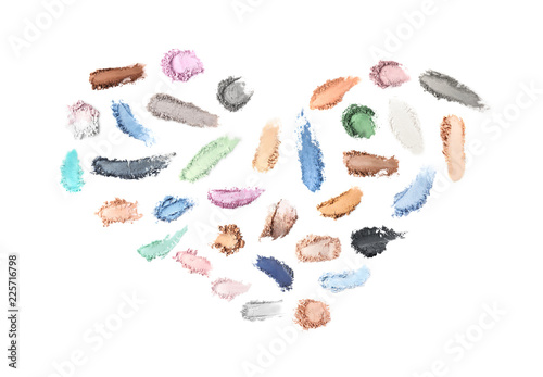 Creative set with different makeup product smears in shape of heart on white background