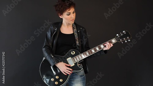 female musician playing the guitar in a black room photo