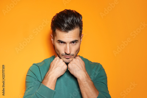 Young man with trendy hairstyle posing on color background