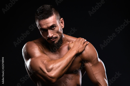 Muscular fitness burnet man is showing bicep putting is hand on the shoulder