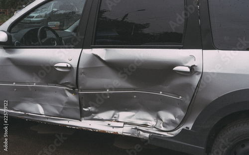 Dented doors on a silver car  after an accident on the road