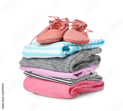 Children's shoes and stack of clothes on white background