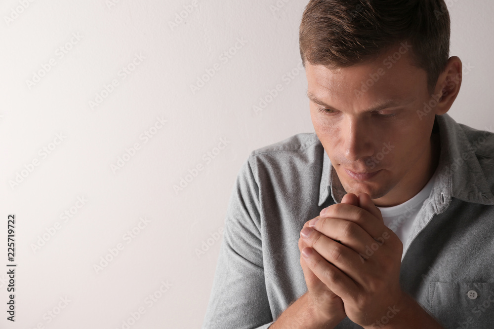 Man with hands clasped together for prayer on light background. Space for text Man with hands clasped together for prayer on light background. Space for text