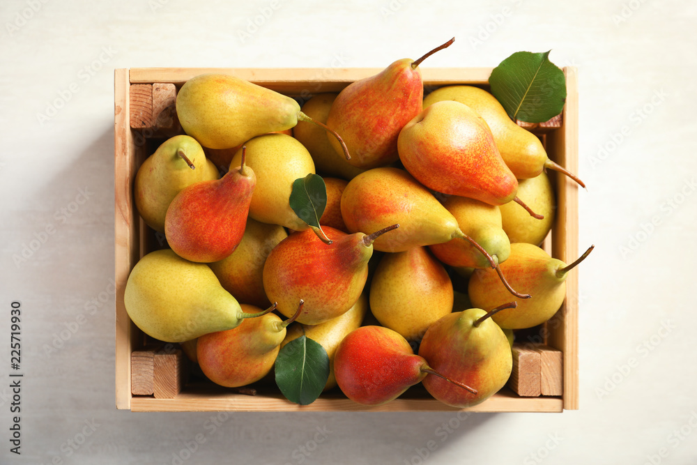 Wooden crate with ripe pears on light background, top view Wooden crate with ripe pears on light background, top view