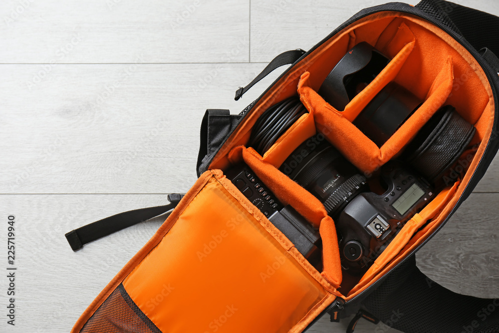 Naklejka premium Bag with digital camera on floor. Professional photographer's equipment