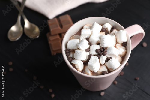 Tasty hot chocolate with milk and marshmallows in cup on table