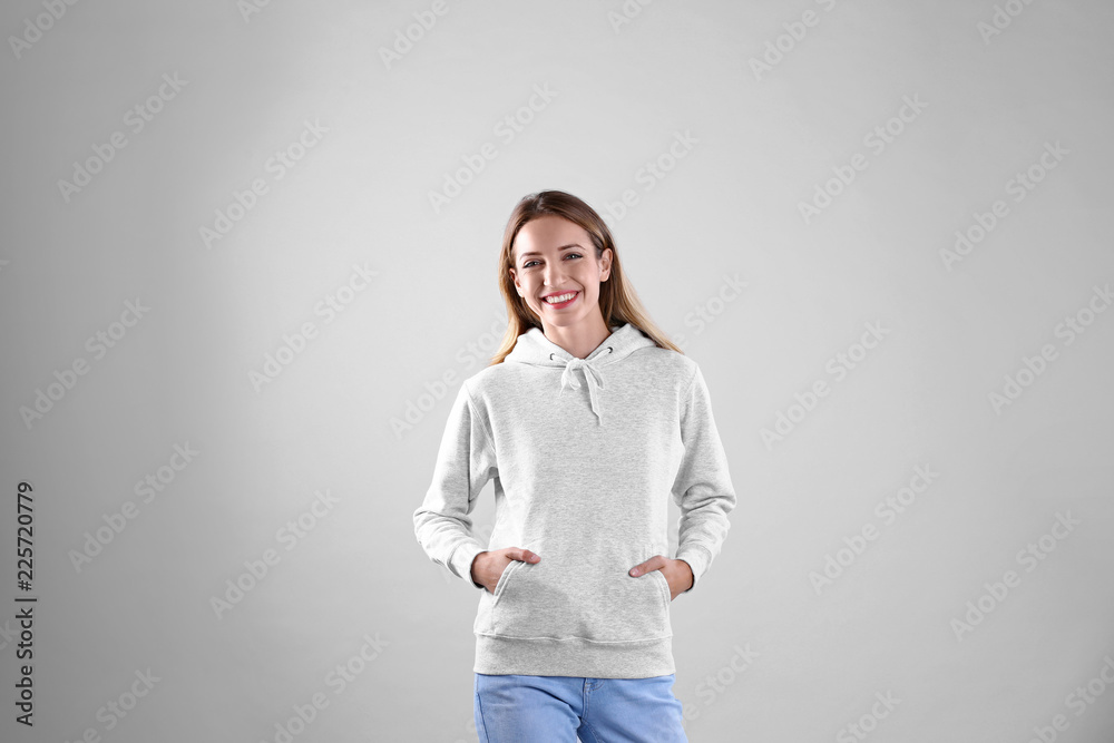 Portrait of woman in hoodie sweater on light background. Space for design Portrait of woman in hoodie sweater on light background. Space for design