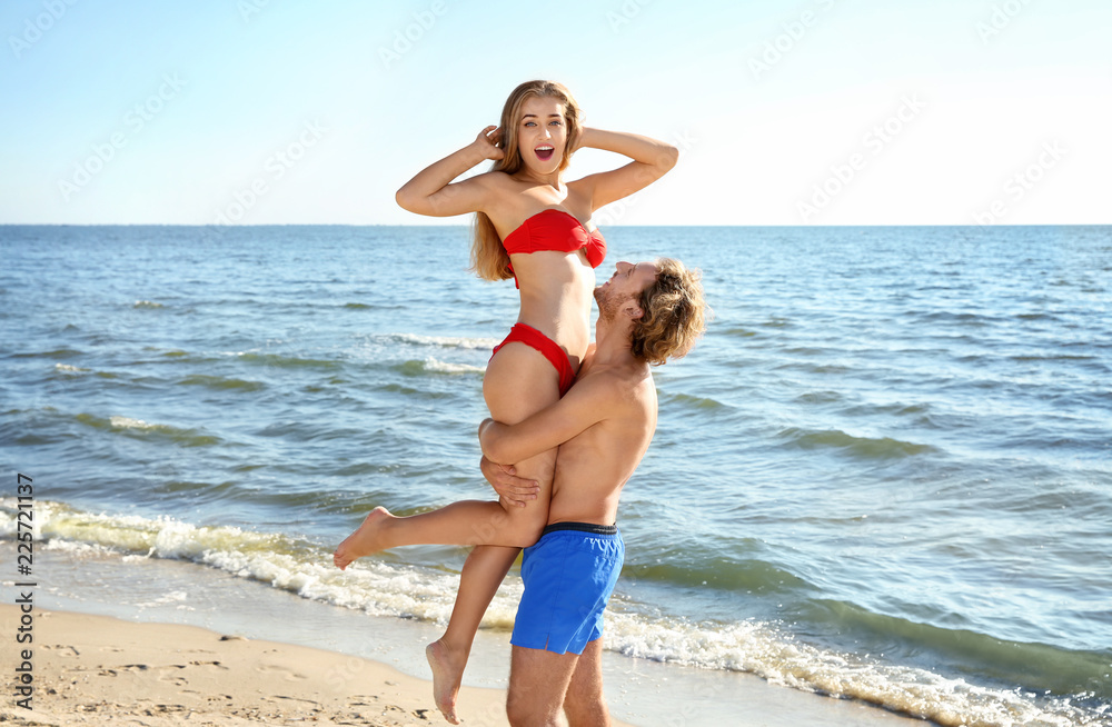 Fototapeta premium Happy young couple in beachwear having fun on seashore