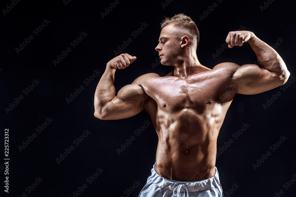 Handsome strong bodybuilder posing in studio on black background
