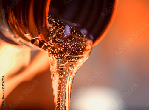 Liquid stream of motorcycle motor oil flows from the neck of the bottle close-up.