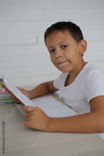 schoolboy teaches lessons, studying books writing in a notebook on a white background