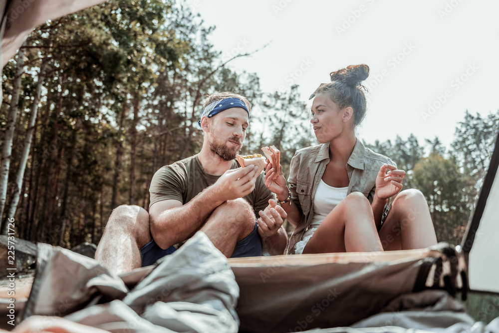 Suntanned backpackers. Suntanned backpackers feeling rested and relaxed while eating delicious sandwiches near their tent