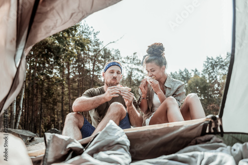 Enjoying taste. Couple of active young hikers feeling satisfied enjoying the taste of vegetable sandwiches after long day © Viacheslav Yakobchuk