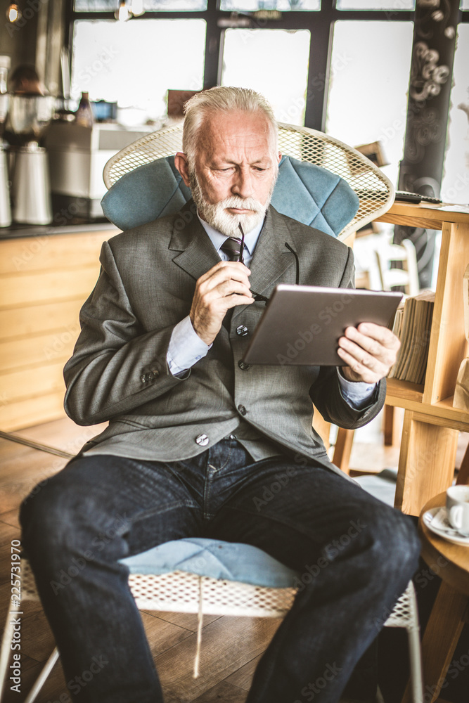 Communications technology. Senior man using digital tablet.