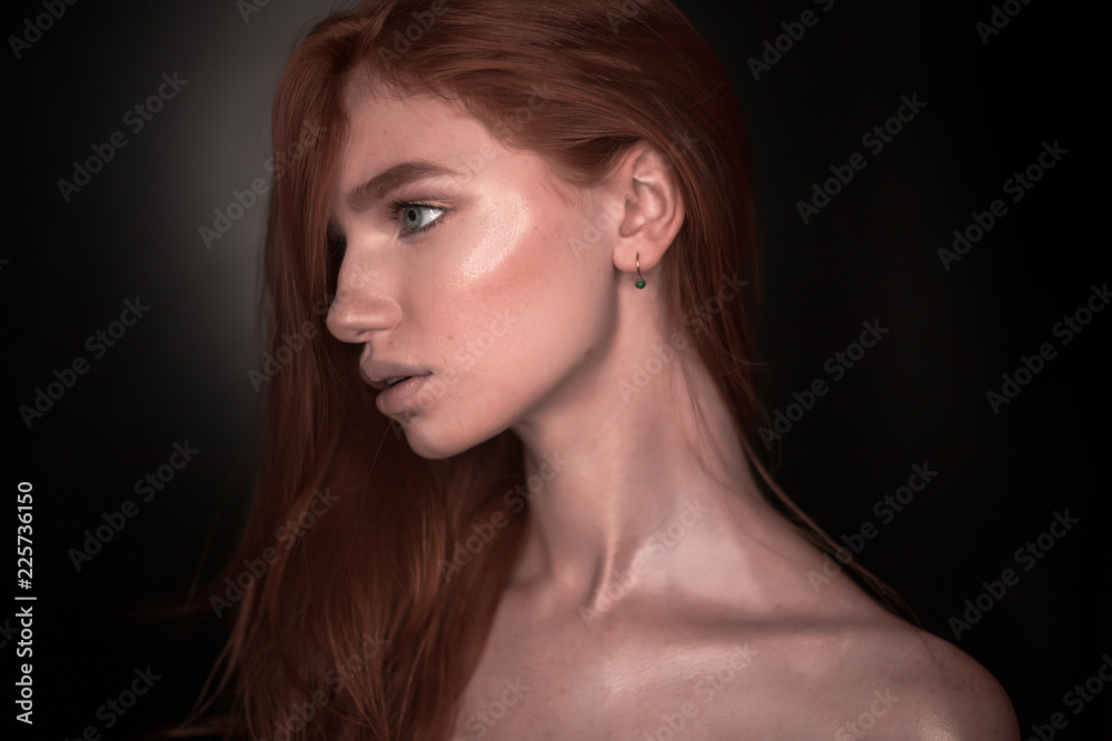 Beautiful serious redhead girl woman with healthy glow wet skin posing isolated over black wall background looking aside to empty copyspace.