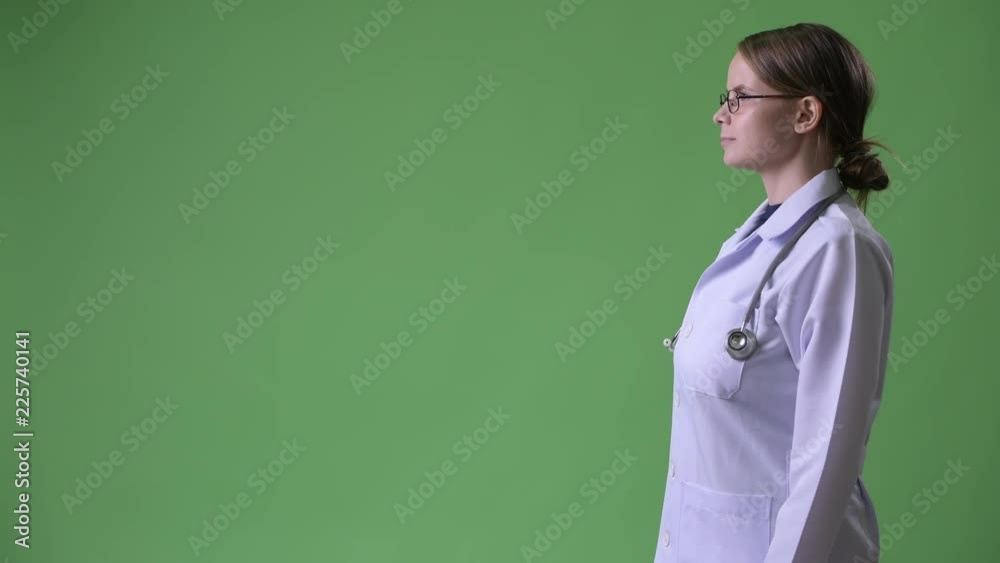 Profile view of young beautiful woman doctor against green background Profile view of young beautiful woman doctor against green background