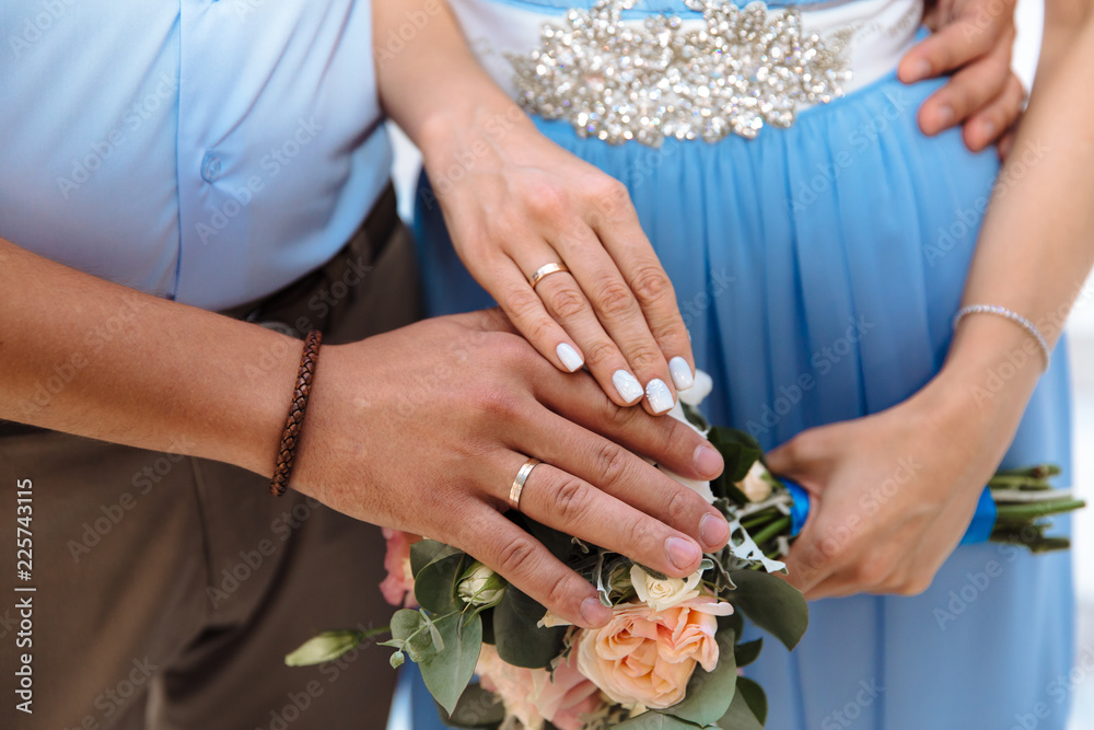 Close-up of the hands of the newlyweds with wedding rings, gently touch the wedding bouquet of peonies. Close-up of the hands of the newlyweds with wedding rings, gently touch the wedding bouquet of peonies.