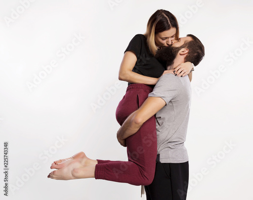 Romantic kisses. Happy young man carrying, hugging and kiss beautiful girl. Lovely couple attractive woman and handsome bearded man isolated on grey