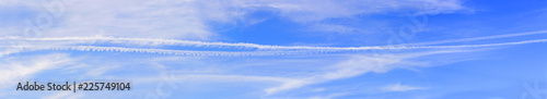 Large blue sky panorama with beautiful white and silver clouds and airplane tracks on the background-wide panoramic view in high resolution and quality