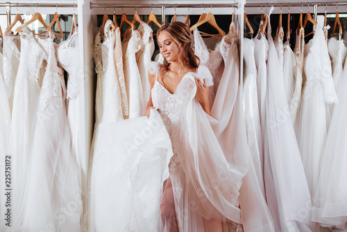 Canvas Print Back view of a young woman in wedding dress looking at bridal gowns