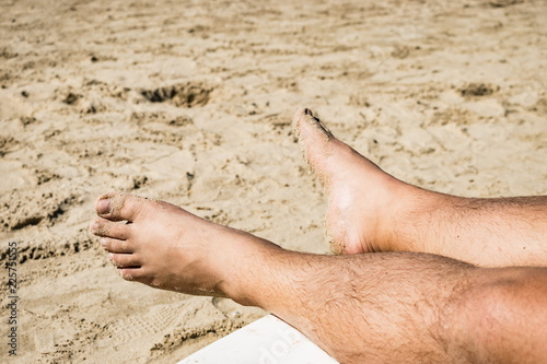Men's feet on lounge in sea view.