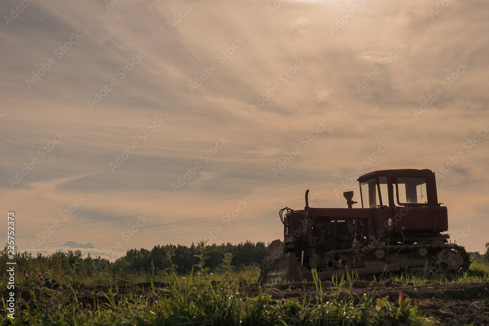 Old abandoned tractor in a plowed field