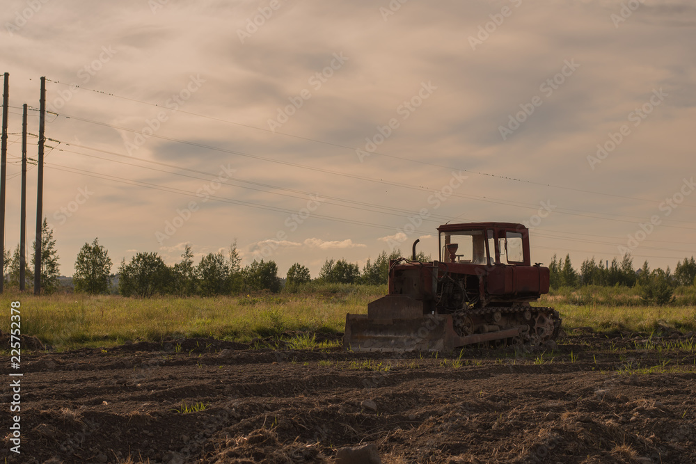 Fototapeta premium Old abandoned tractor in a plowed field