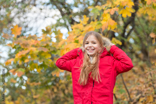 Feel cozy in warm jacket. Girl happy wear coat with hood enjoy fall nature. Child wear coat for fall season. Fall clothes and fashion concept. Child blonde long hair walking fall park background