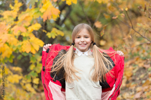 Girl happy wear coat with hood enjoy fall nature. Child wear coat for fall season. Fall clothes and fashion concept. Child blonde long hair walking fall park background. Feel cozy in warm jacket photo