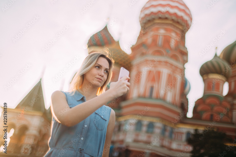 Beautiful girl makes a photo on the background of the Kremlin. Middle shot. Sunny