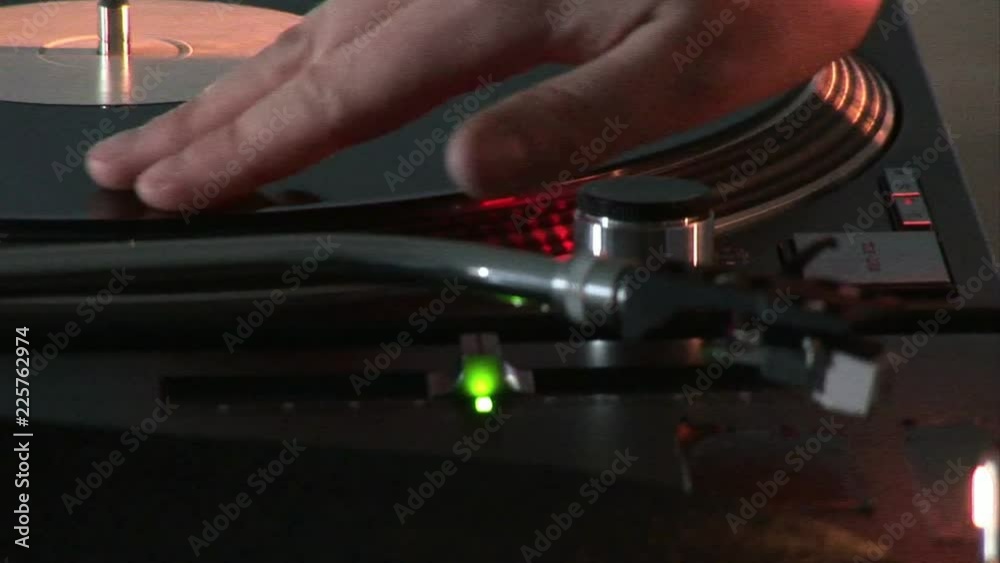 Loop of Close up of a dj scratching a disc on his mixer during a party