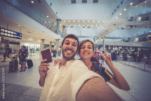 Happy young smiling caucasian couple traveler having fun at airport terminal holding passport. Travel and lover concept