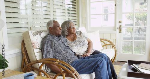 Mature black couple sitting on couch looking away