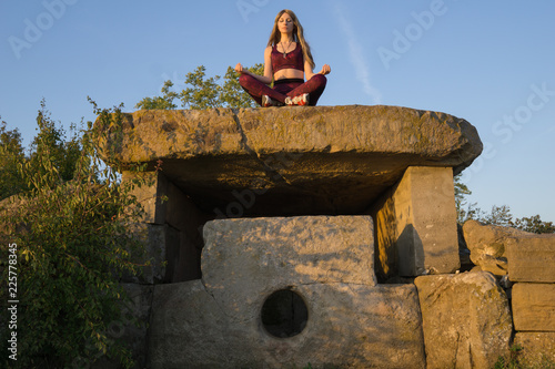 Girl meditating on ancient stone Dolmen