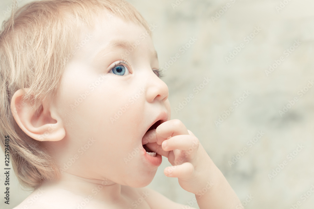 Hungry child with blue eyes puts food in his mouth.