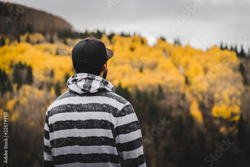 A man looking out into the distance of a mountain covered in fall foliage.  photo