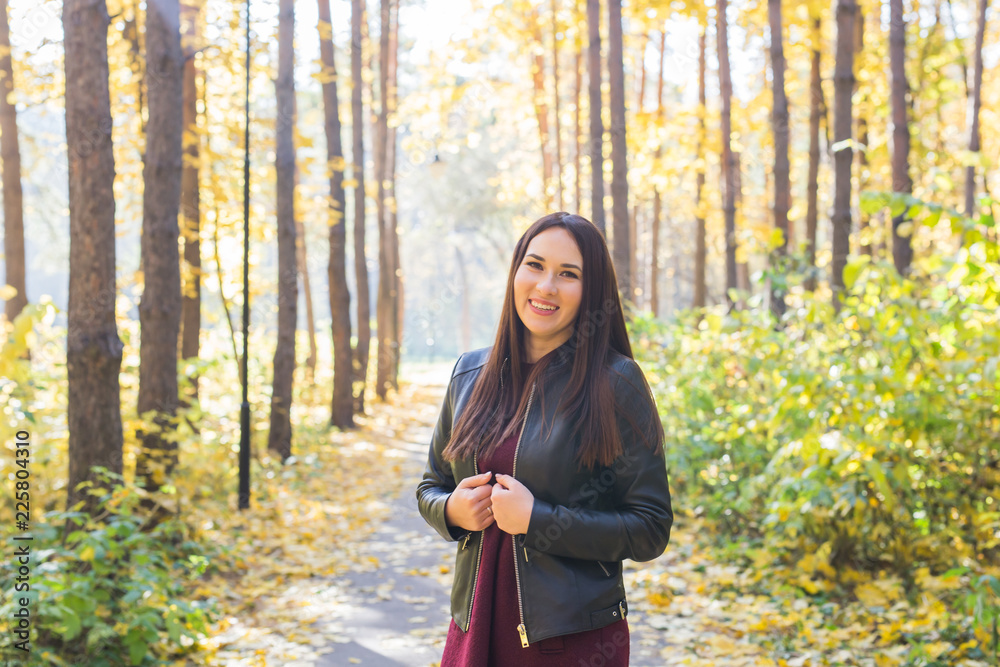 Fall, season and people concept - young brunette woman standing in park at autumn Fall, season and people concept - young brunette woman standing in park at autumn