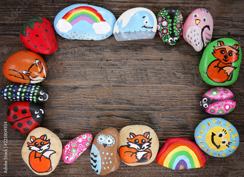 Border of Colorful Cartoon Hand Painted Animal Rocks on Wood Background