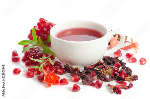 Parts of a pomegranate with pomegranate seeds and leaves, flowers, dry tea of carcade and full cup of tea isolated on white background photo